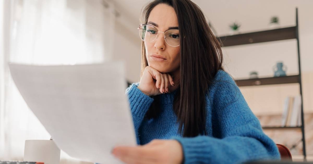 Focused woman reading financial documents at home